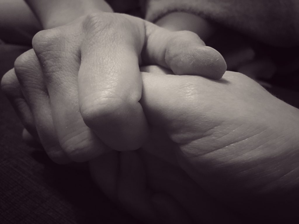 Two hands holding each other snugly. Image licensed through Adobe stock.