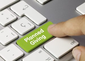 A person pressing a button on a keyboard that is green and labeled "Planned Giving." Image licenced from Adobe Stock.