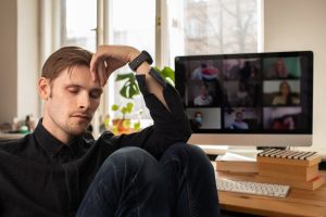 Man fatigued during home video conference meeting call. Image licensed through Adobe Stock.