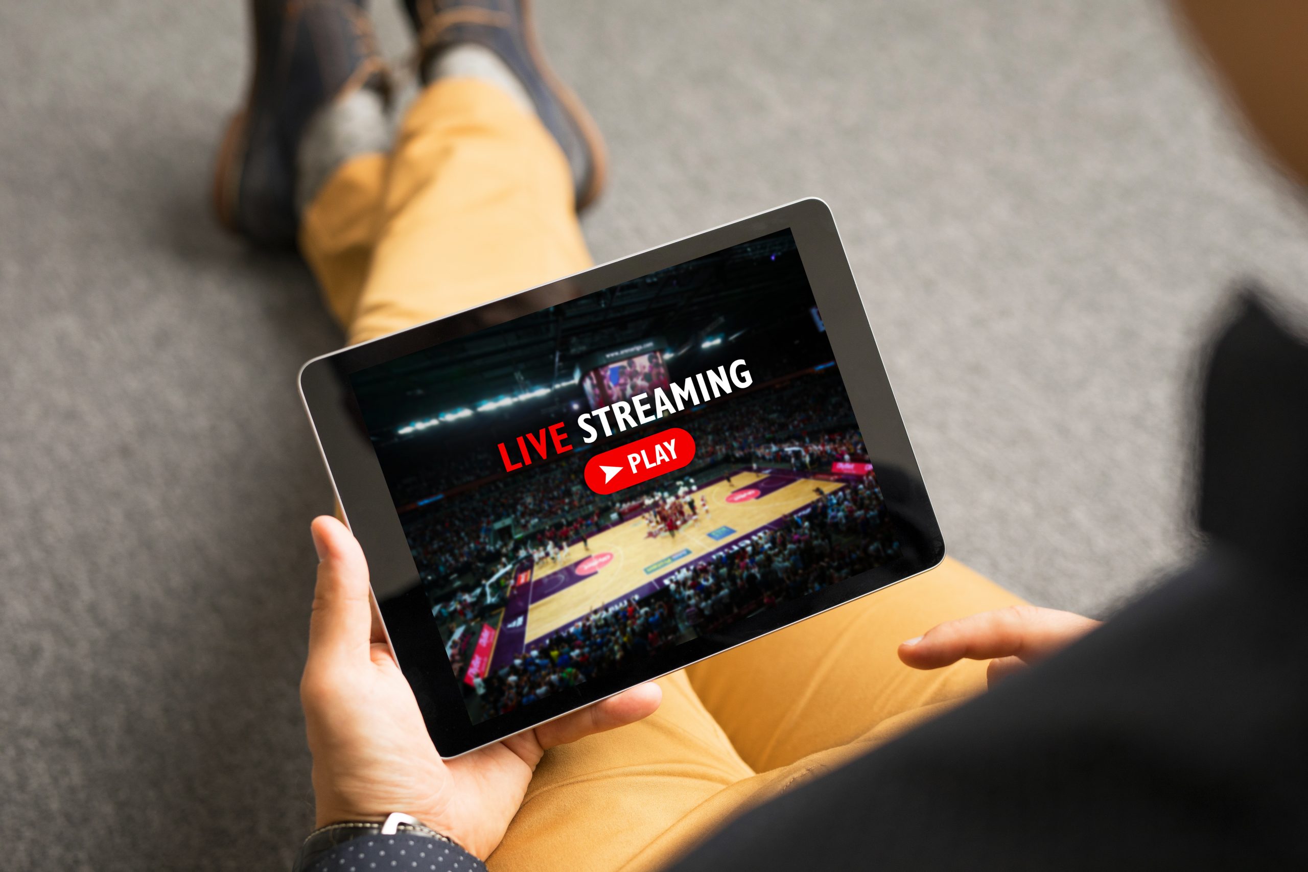 Person looking at sports streaming on a tablet. Image licensed through Adobe Stock.