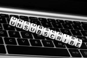 Lettered beads lined up on a keyboard to spell "unsubscribe." Licensed through Adobe Stock.