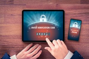 Two-factor authentication (2FA) and verification security concept. User with digital tablet and smart phone and two-factor authentication security process. Image licensed through Adobe Stock.