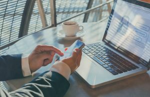 Well-dressed person using an SMS message to confirm security on their laptop. Image licensed through Adobe Stock.