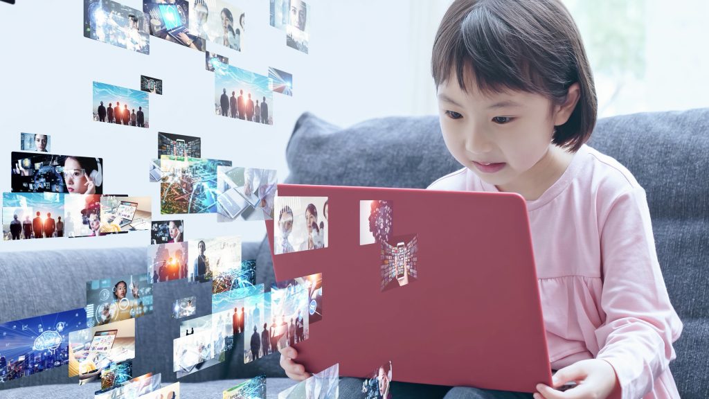 A child watching movies on a computer with images on the screen streaming towards it. Image licensed through Adobe Stock.