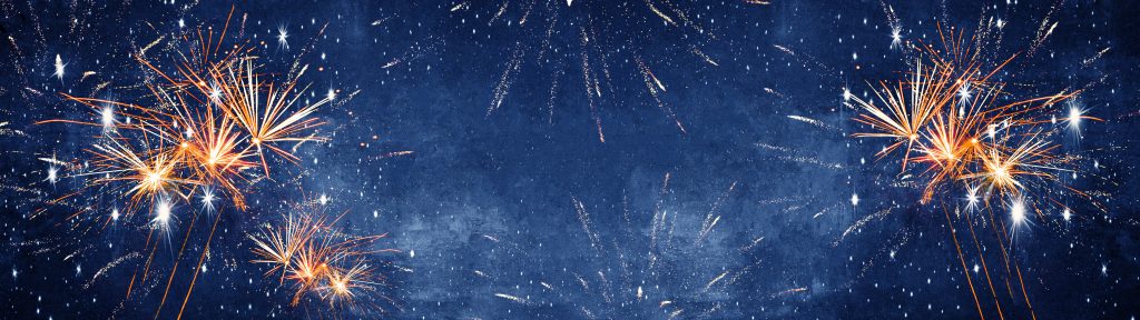 Fireworks over a blue and white clouded sky. Image licensed through Adobe Stock.