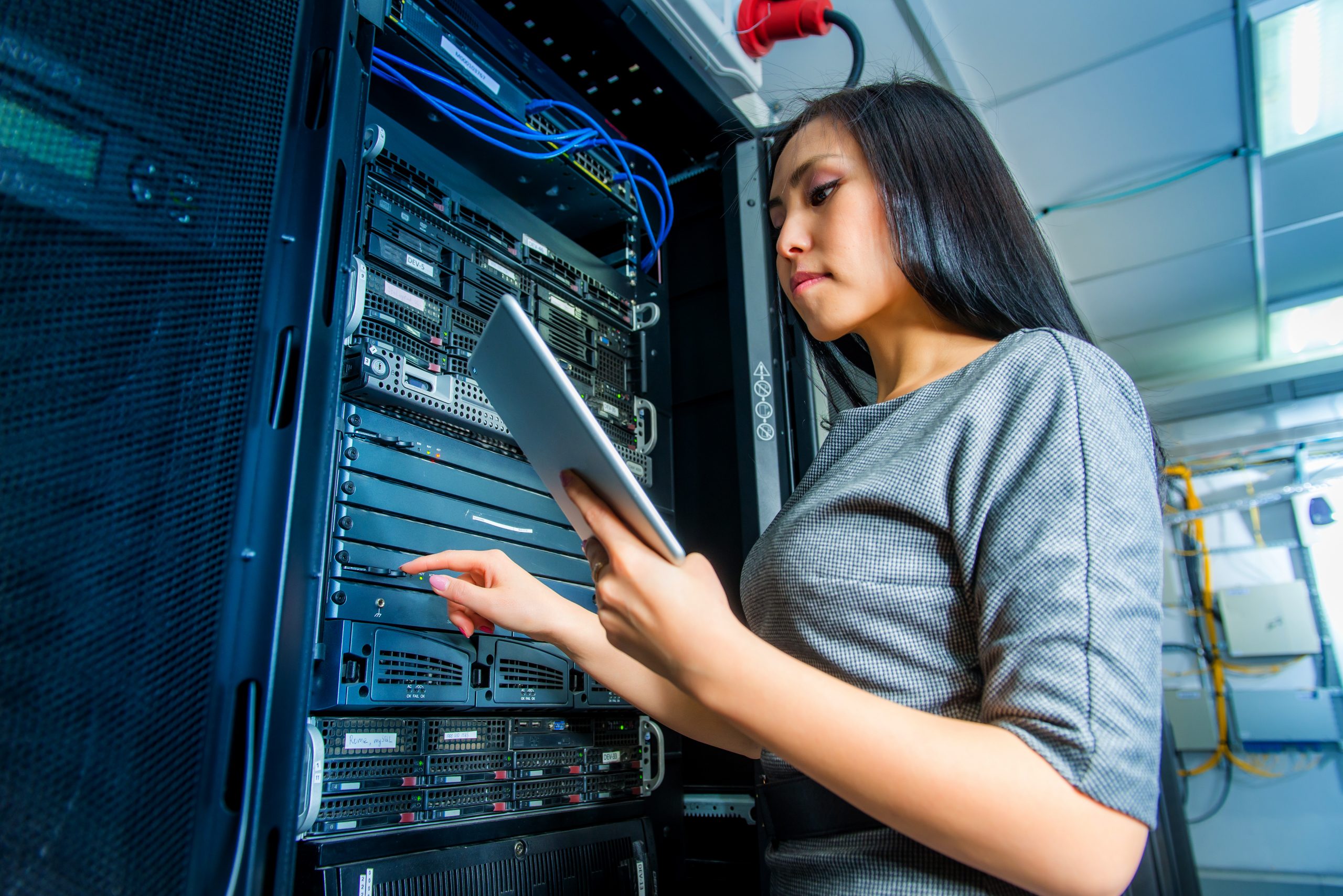 Young engineer businesswoman with tablet in network server room. Image licensed through Adobe Stock.