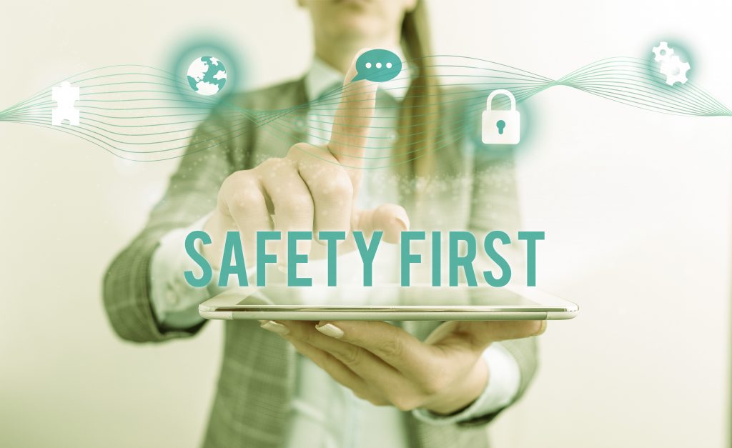 A woman pressing buttons in the air as if a hologram behind the text Safety First. Image licensed through Adobe Stock.