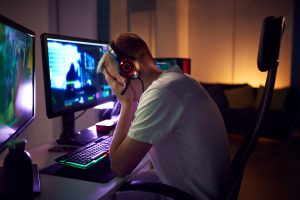 Stressed teenage boy being bullied online while gaming at home. Image licensed through Adobe Stock.