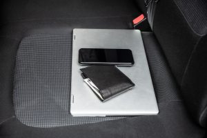 A phone, wallet, and laptop left on a car seat. Image licensed through Adobe Stock.