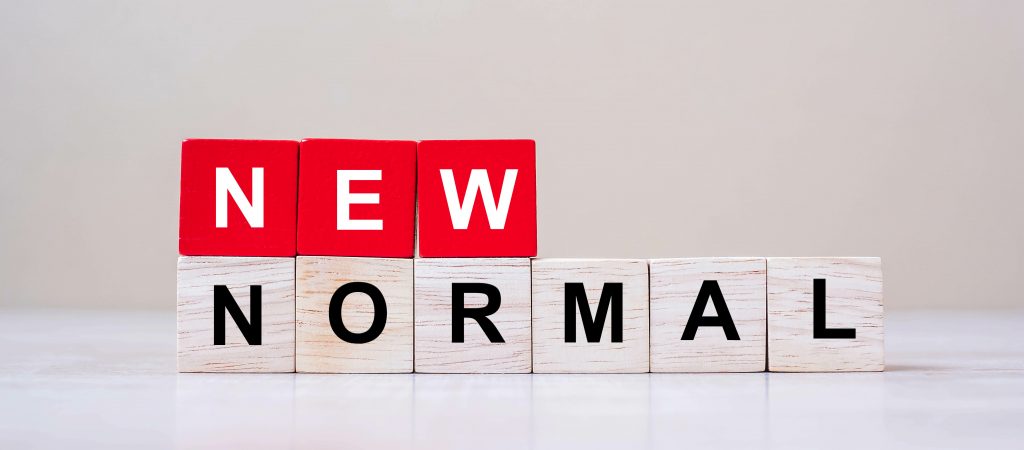 A white space with standing tiles in red and white spelling out the words "New Normal." Image licensed through Adobe Stock.